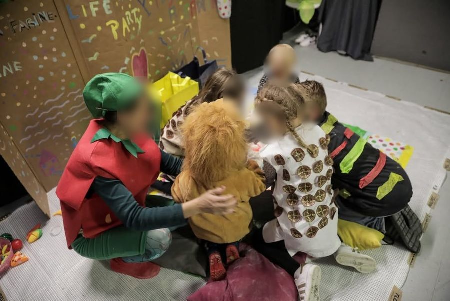 Enfants en atelier créatif autour d'un costume de lion, visages floutés