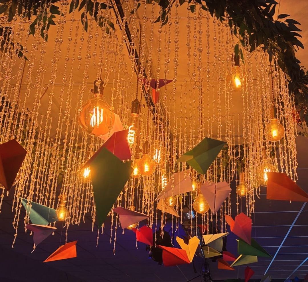 Plafond décoré d'avions en papier et de rideaux de lumière lors d'une Life Party