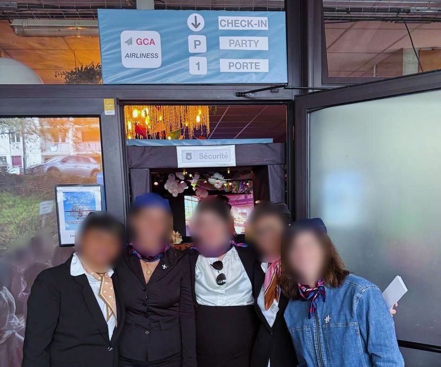 L'équipe d'accueil en tenue d'hôtesse devant l'entrée décorée, visages floutés